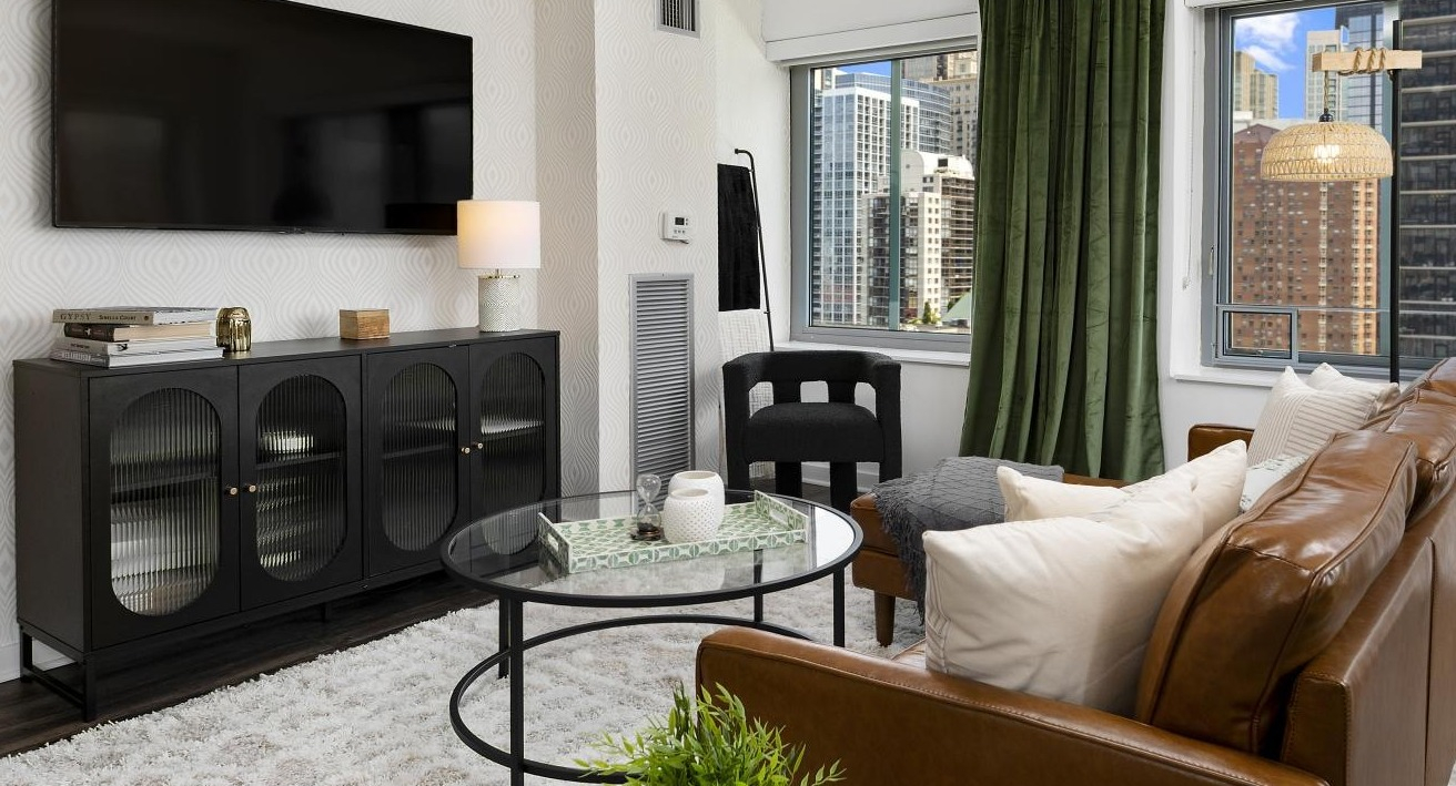 A cozy living room at Chestnut Towers with a modern media console, plush seating, and large windows with city views