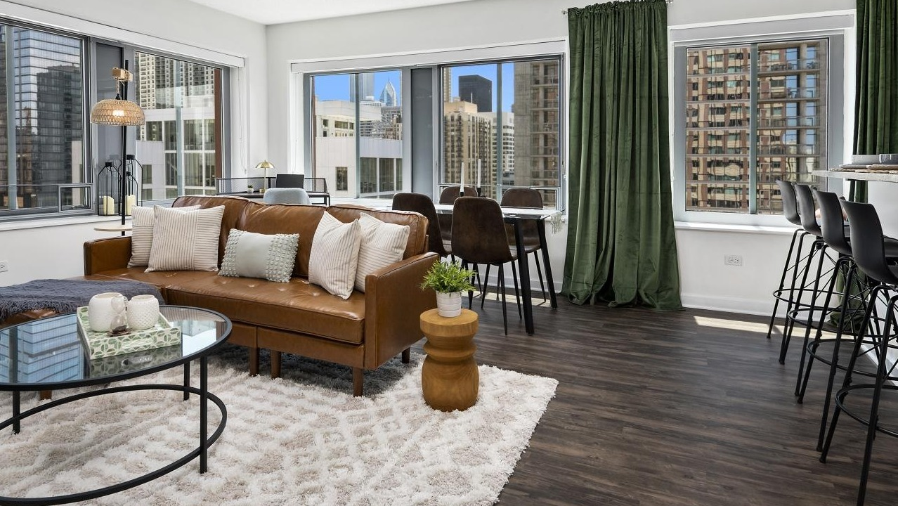 A welcoming living room at Chestnut Towers, featuring a modern brown leather sofa, stylish rug, and city views