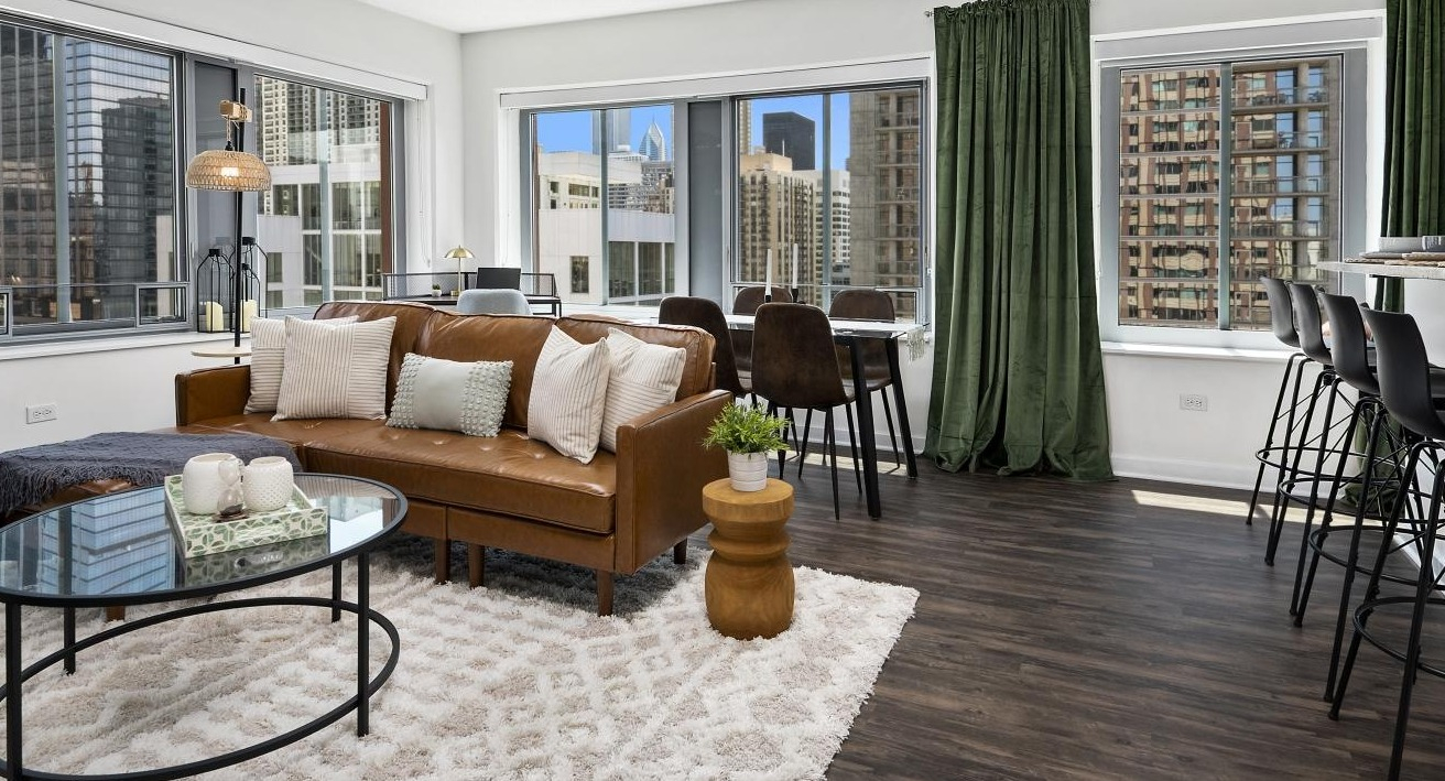A welcoming living room at Chestnut Towers, featuring a modern brown leather sofa, stylish rug, and city views