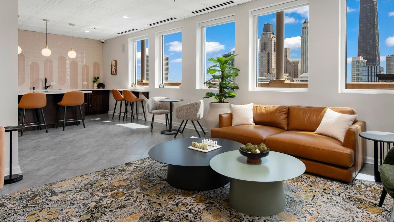 A spacious resident lounge at Chestnut Towers, featuring comfortable seating, a bar area, and stunning city views