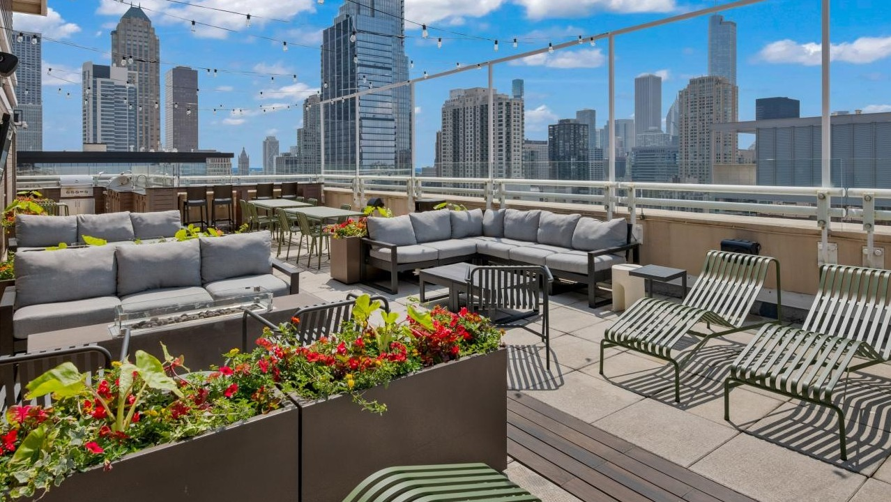 An inviting rooftop lounge area at Chestnut Towers with comfortable seating, lush plants, and city skyline views