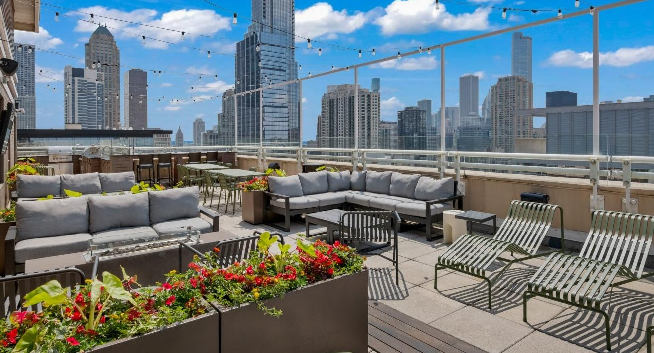 An inviting rooftop lounge area at Chestnut Towers with comfortable seating, lush plants, and city skyline views