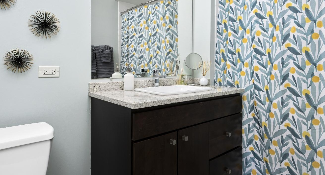  A bright bathroom at Chestnut Towers, boasting a stylish vanity, patterned shower curtain, and contemporary wall decor