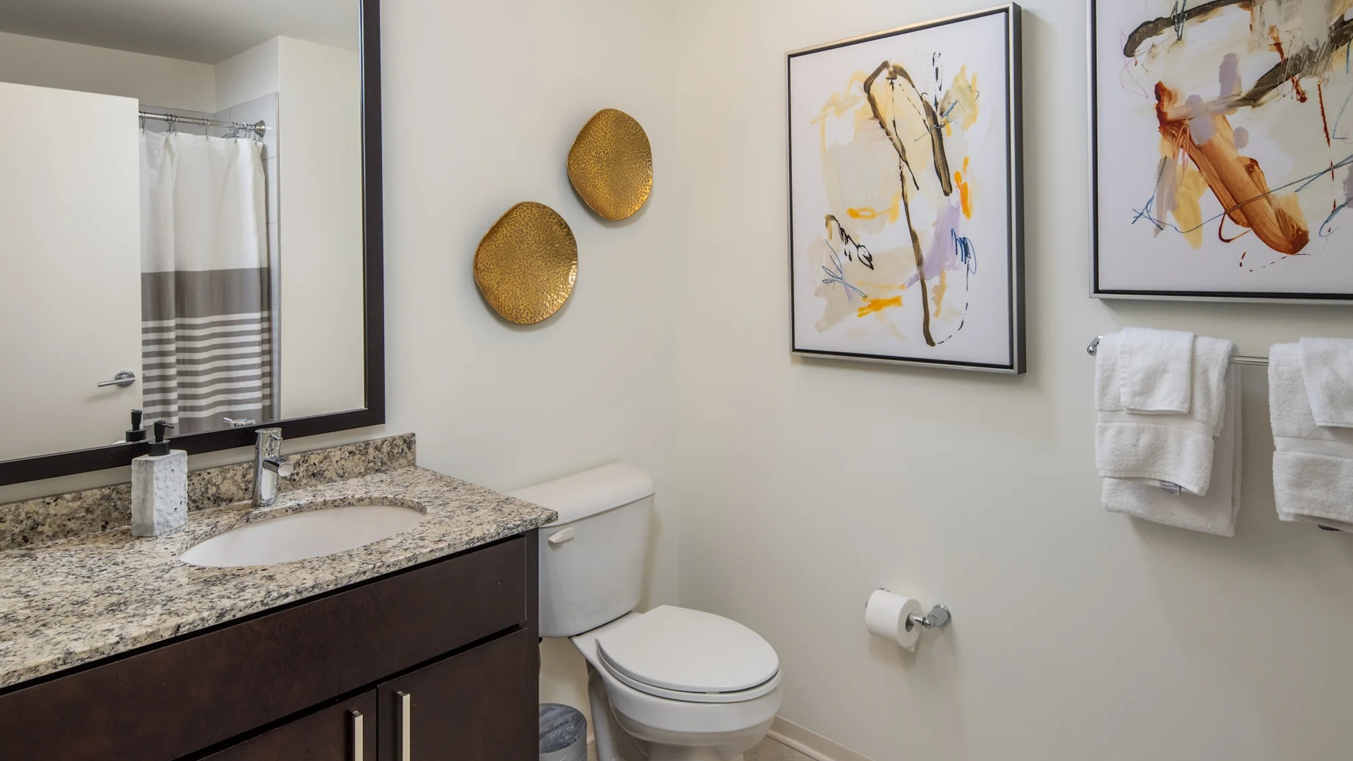 Cozy bathroom featuring a granite vanity, large mirror, and artistic wall decor at Circa 922 apartments in Chicago