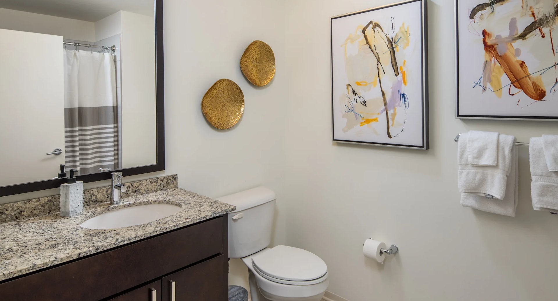 Cozy bathroom featuring a granite vanity, large mirror, and artistic wall decor at Circa 922 apartments in Chicago