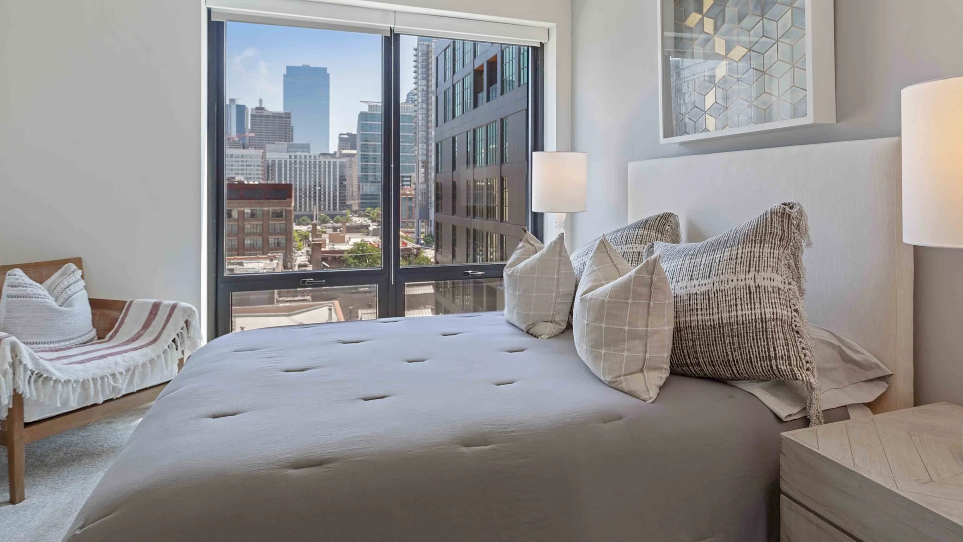 Cozy bedroom with a large window offering stunning city views, a comfortable bed, and modern minimalist decor at Circa 922 in Chicago