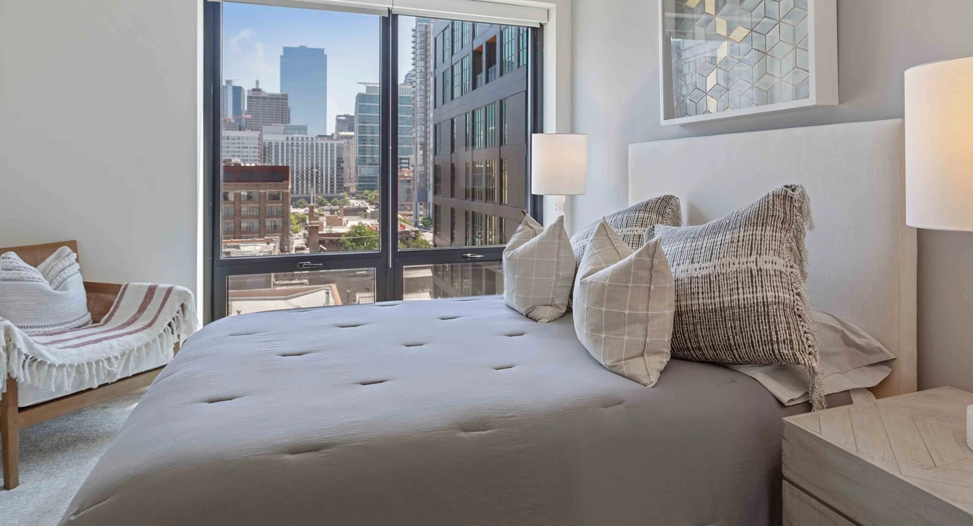 Cozy bedroom with a large window offering stunning city views, a comfortable bed, and modern minimalist decor at Circa 922 in Chicago