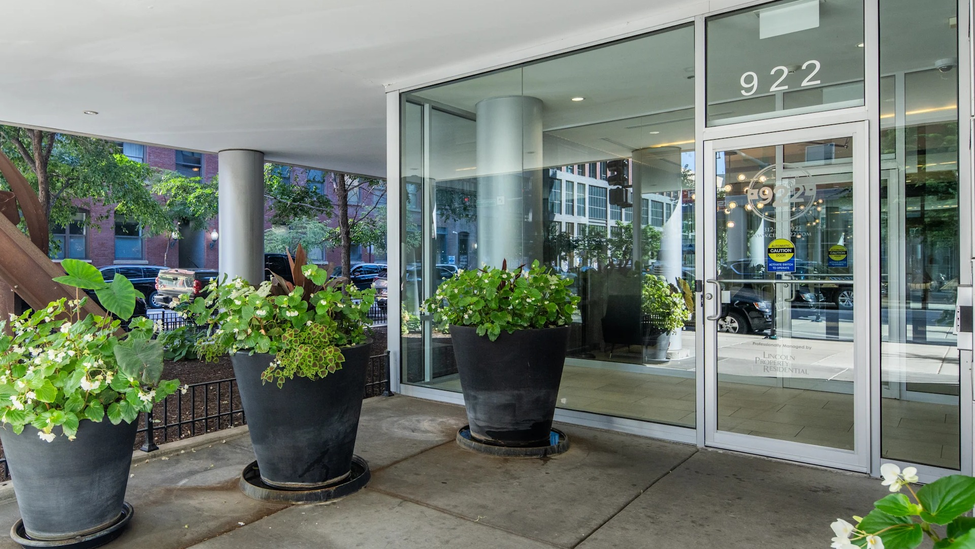 Grand entrance to Circa 922 apartments in Chicago, featuring large glass doors and decorative planters