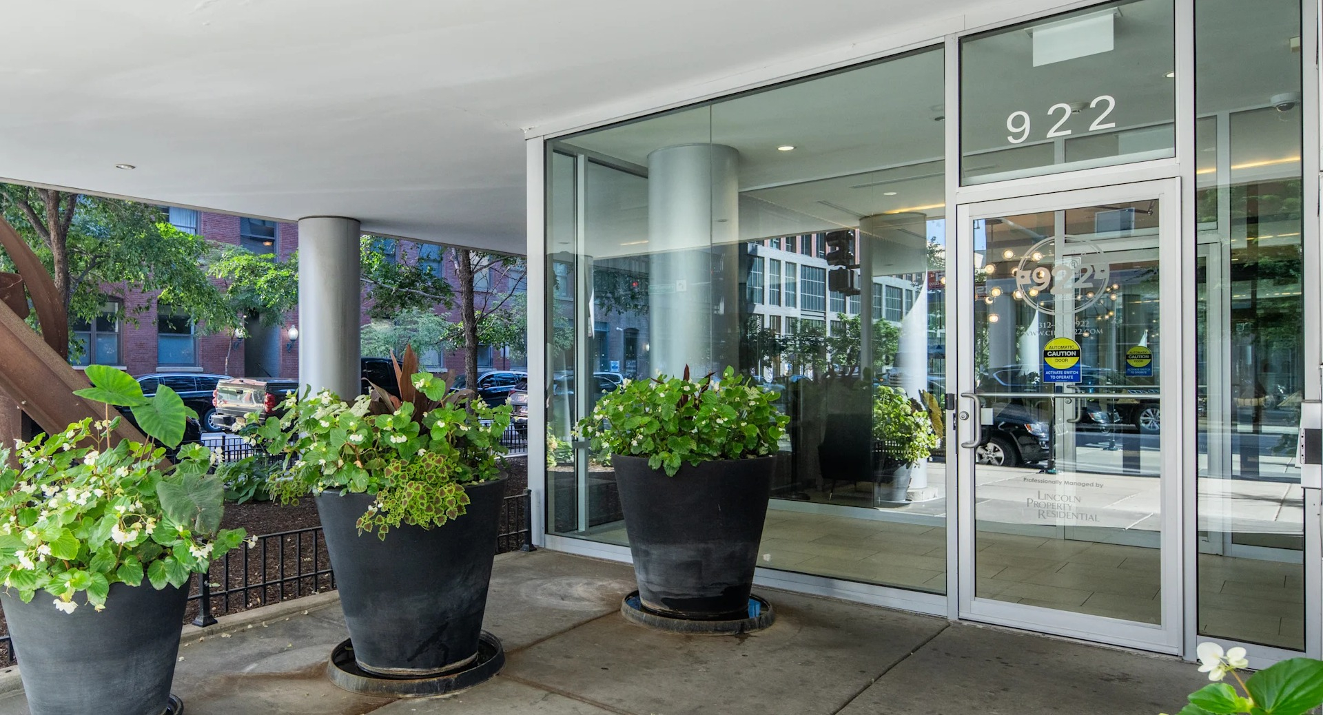 Grand entrance to Circa 922 apartments in Chicago, featuring large glass doors and decorative planters