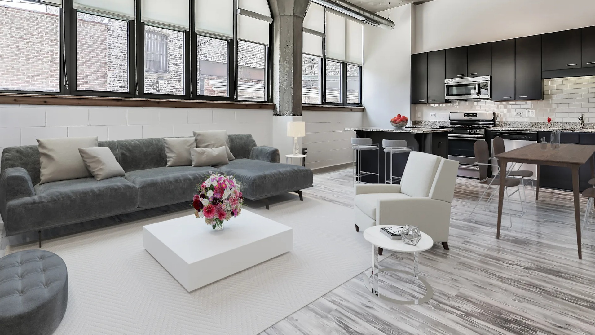 Spacious open-concept living room and kitchen featuring industrial elements, modern appliances, and a large sectional sofa at Circa 922 in Chicago