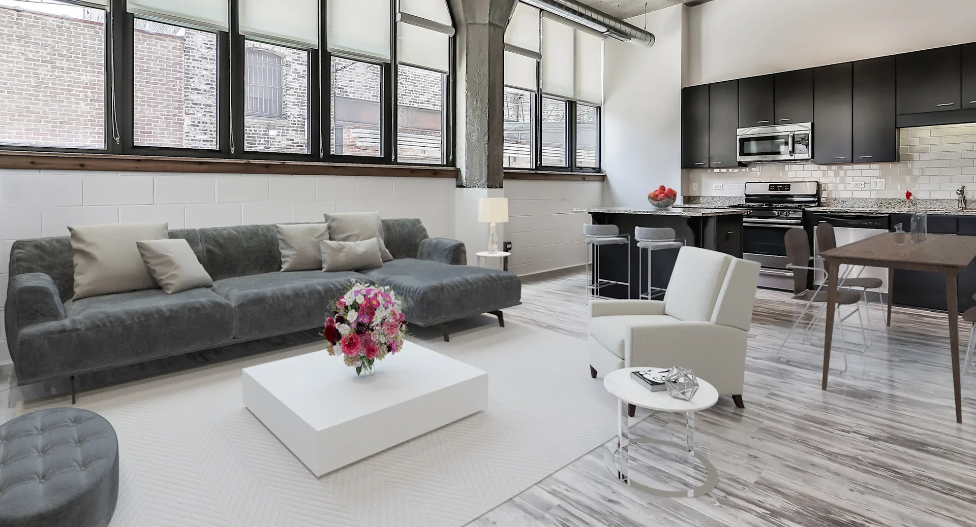 Spacious open-concept living room and kitchen featuring industrial elements, modern appliances, and a large sectional sofa at Circa 922 in Chicago