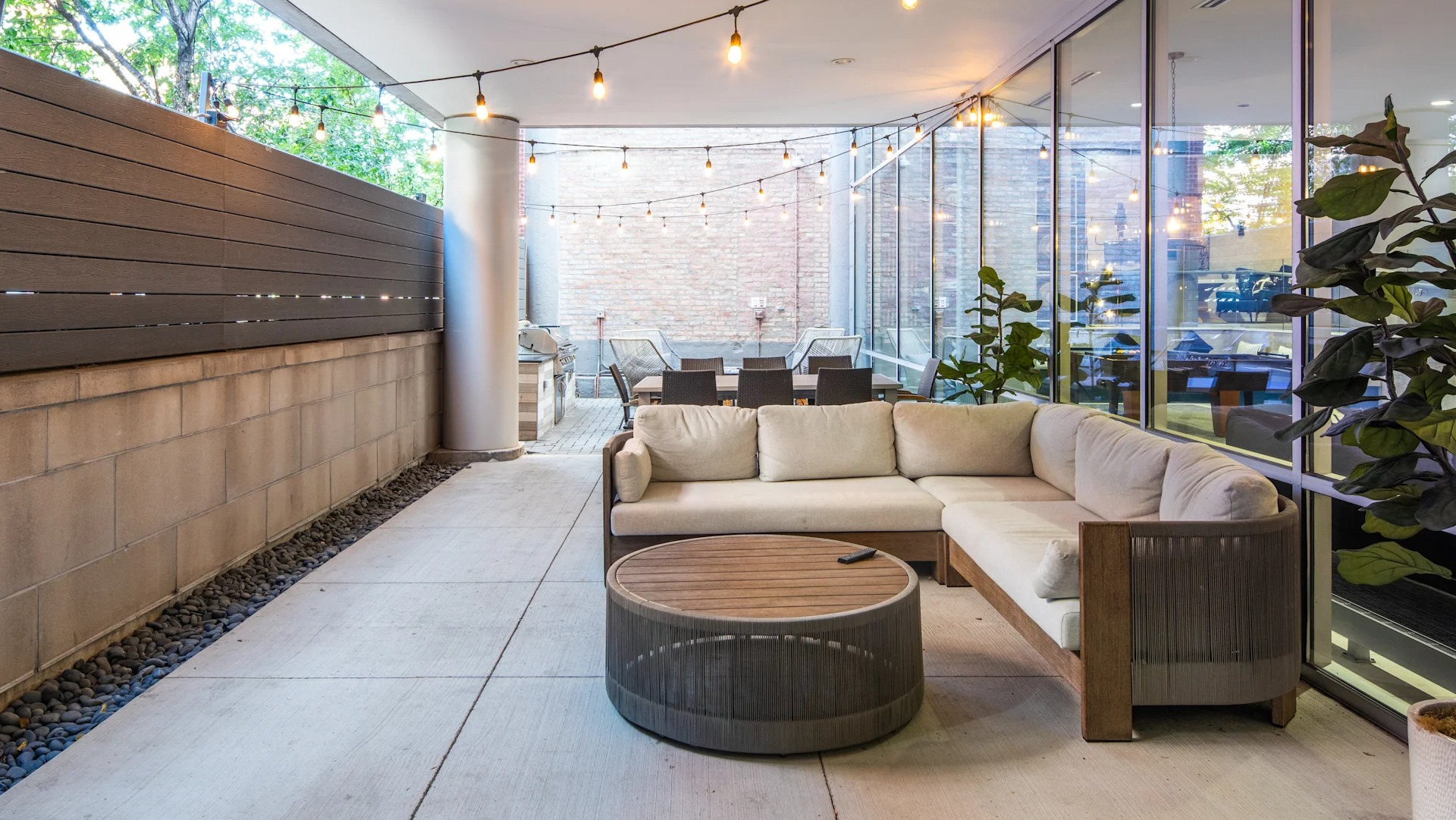 Covered outdoor lounge patio with comfortable sectional seating, string lights, and a large screen for entertainment at Circa 922 in Chicago