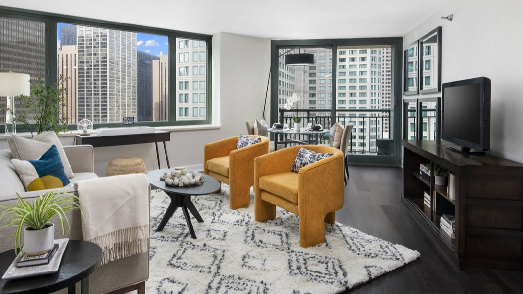 Bright living room and dining area at Cityfront Place with vibrant yellow armchairs, a cozy rug, and city views