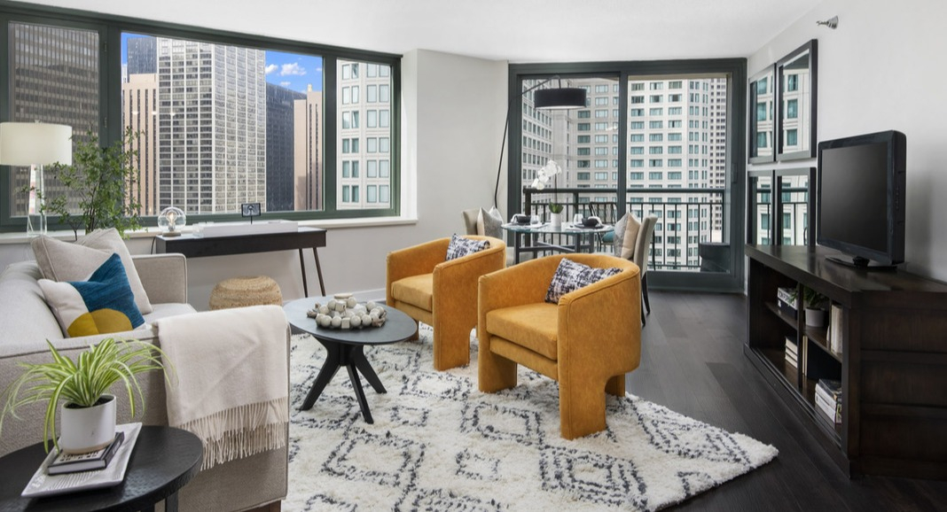 Bright living room and dining area at Cityfront Place with vibrant yellow armchairs, a cozy rug, and city views