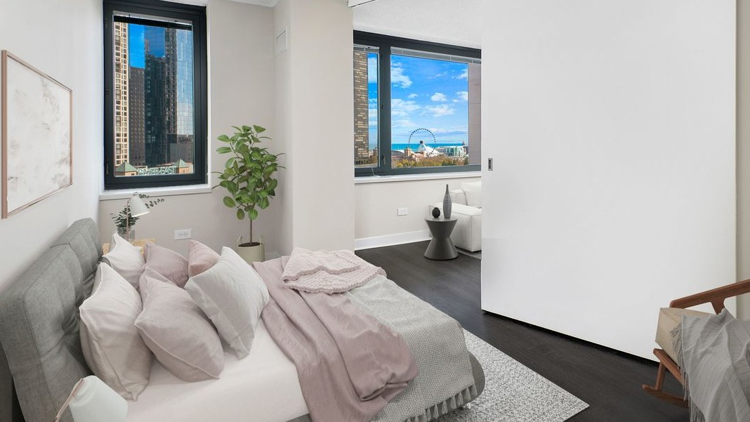 Cozy bedroom at Cityfront Place featuring a comfortable bed, large windows, and a modern sliding door