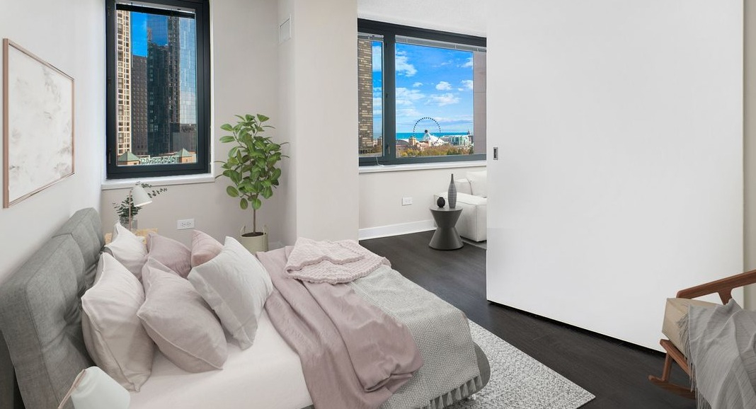 Cozy bedroom at Cityfront Place featuring a comfortable bed, large windows, and a modern sliding door