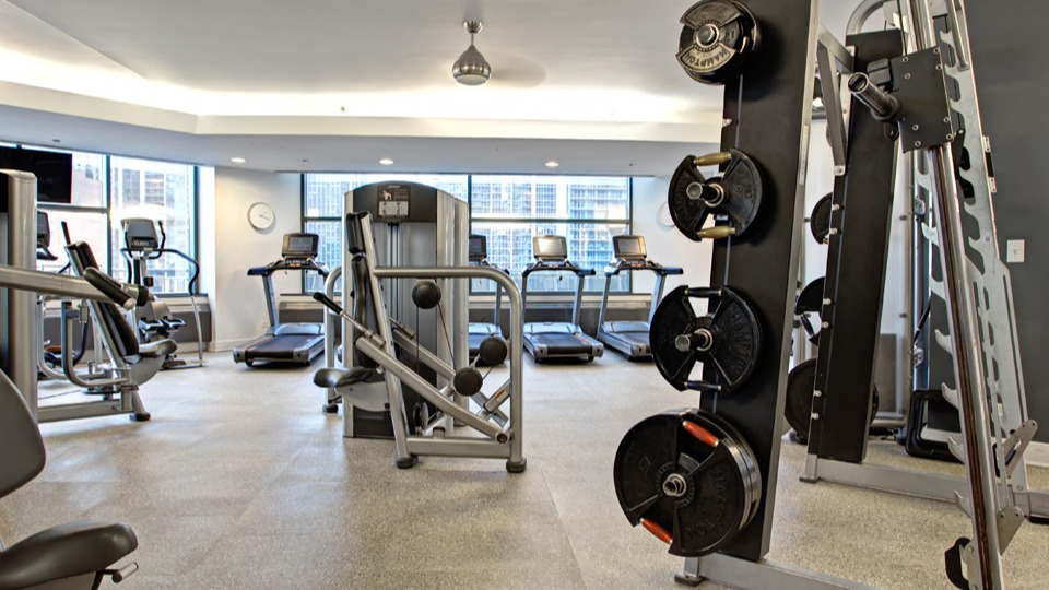 Well-equipped fitness center at Cityfront Place with weight machines, free weights, and treadmills overlooking the city
