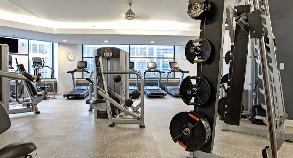 Well-equipped fitness center at Cityfront Place with weight machines, free weights, and treadmills overlooking the city