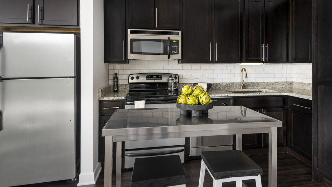 Modern gourmet kitchen at Cityfront Place with dark cabinetry, stainless steel appliances, and a central island
