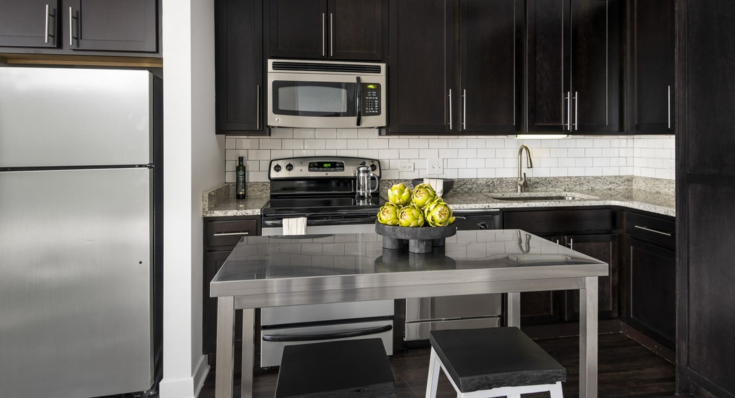 Modern gourmet kitchen at Cityfront Place with dark cabinetry, stainless steel appliances, and a central island