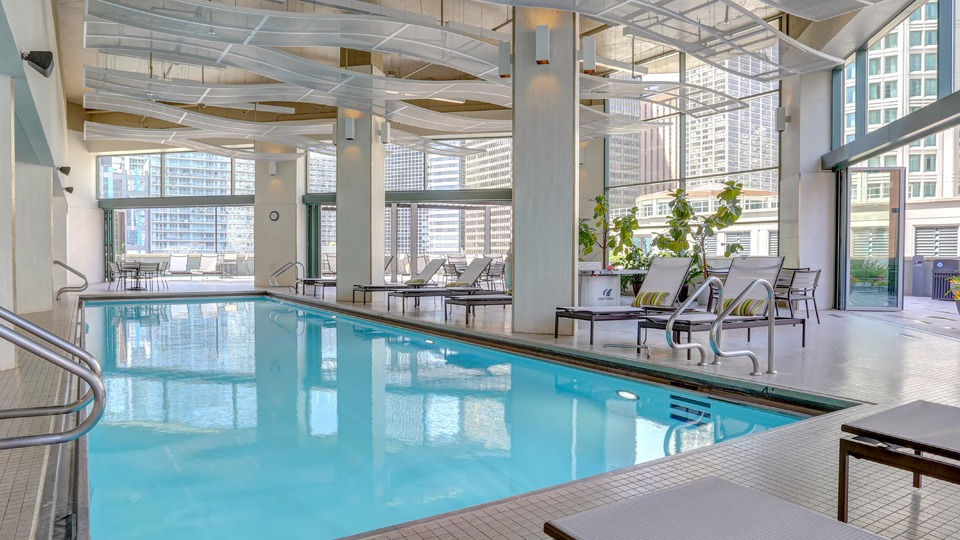 Inviting indoor swimming pool at Cityfront Place with lounge chairs and large windows overlooking the city