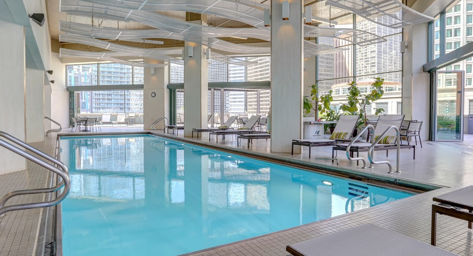 Inviting indoor swimming pool at Cityfront Place with lounge chairs and large windows overlooking the city