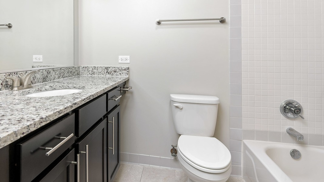 Modern bathroom at Cityfront Place with a vanity, granite countertop, a toilet, and a bathtub with shower