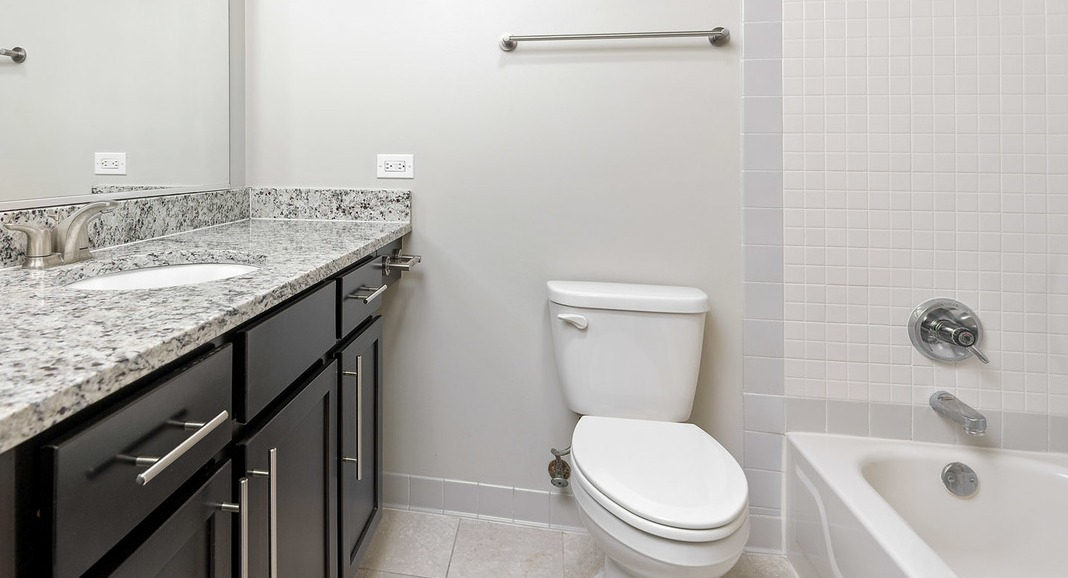 Modern bathroom at Cityfront Place with a vanity, granite countertop, a toilet, and a bathtub with shower