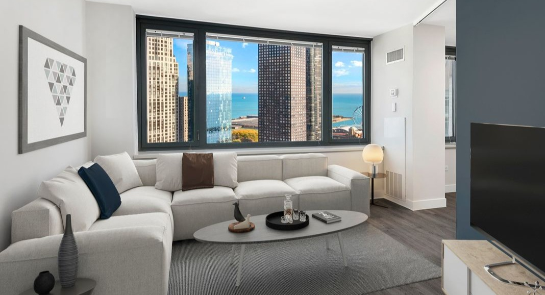 Spacious living room at Cityfront Place with a plush sectional, contemporary decor, and stunning views of Lake Michigan