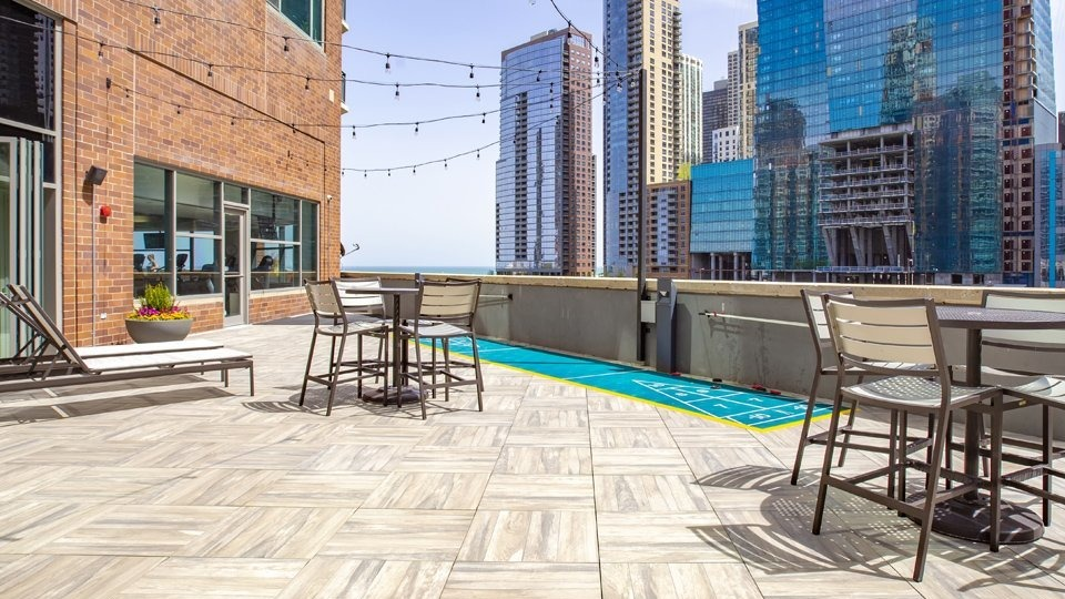 Expansive rooftop deck at Cityfront Place with outdoor seating, string lights, and a shuffleboard court