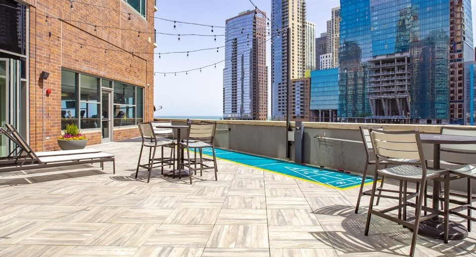 Expansive rooftop deck at Cityfront Place with outdoor seating, string lights, and a shuffleboard court