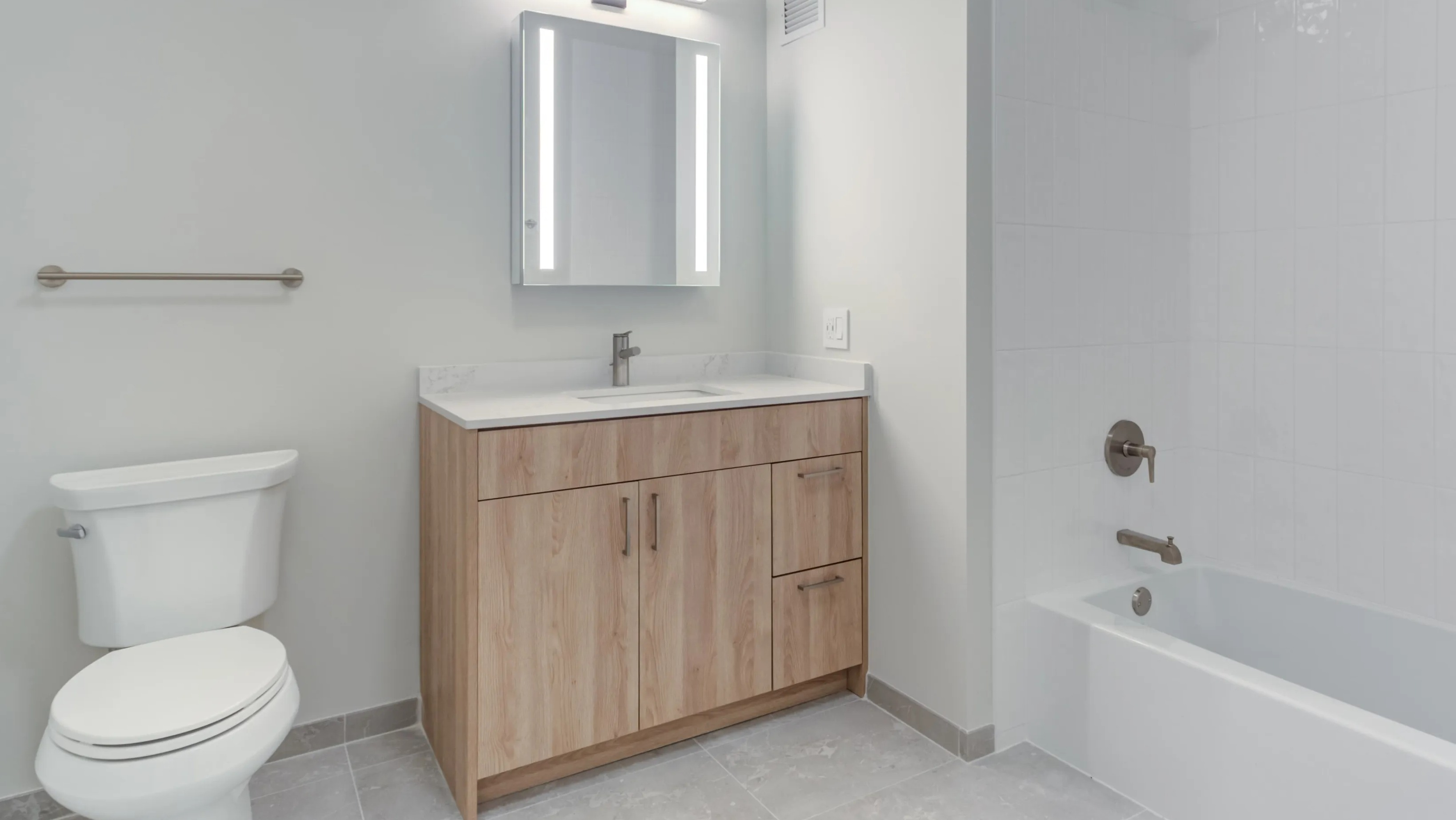 A bright, modern bathroom at Coast at Lakeshore East with a light wood vanity, white tiled shower, and sleek fixtures