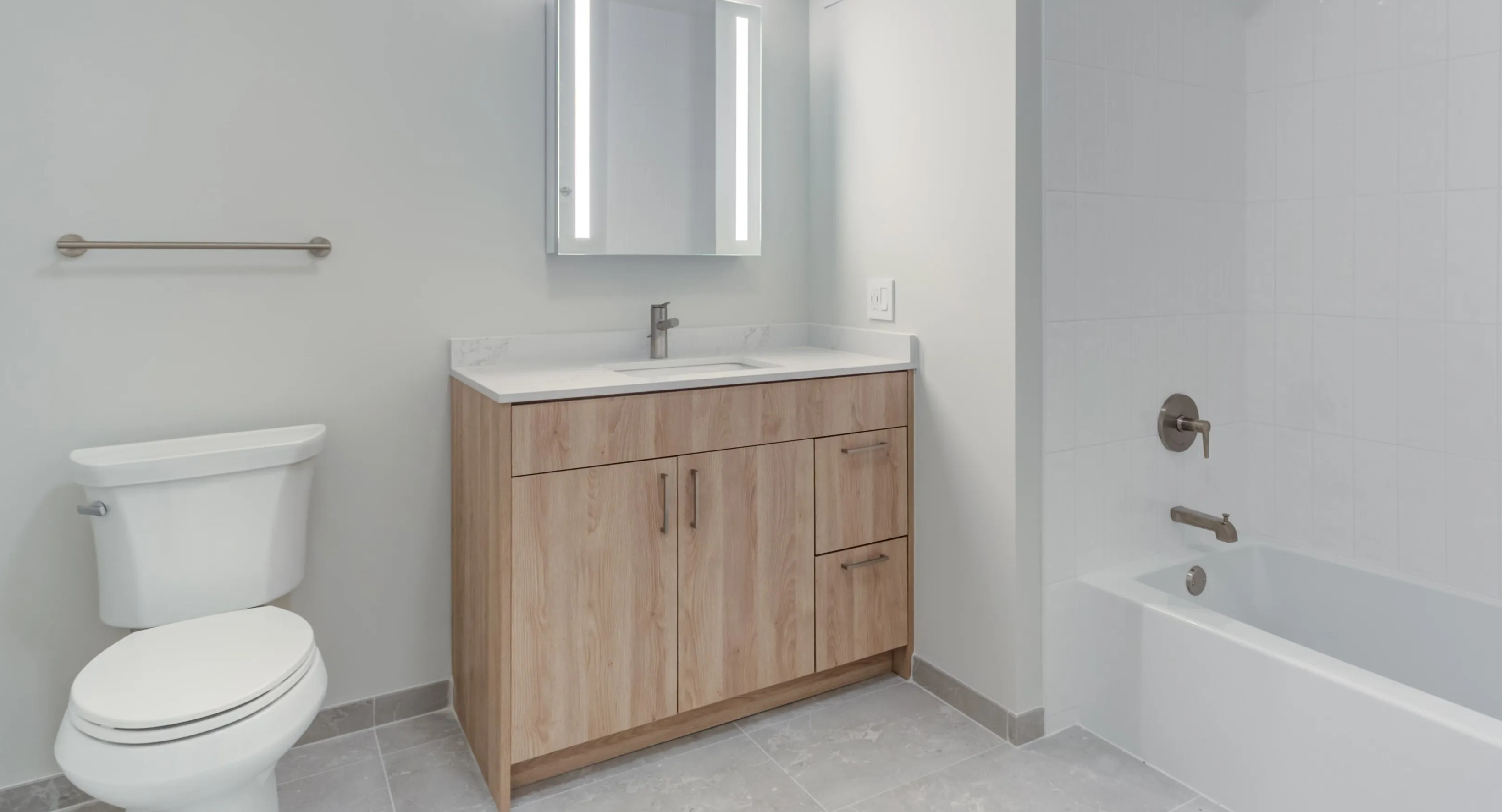 A bright, modern bathroom at Coast at Lakeshore East with a light wood vanity, white tiled shower, and sleek fixtures
