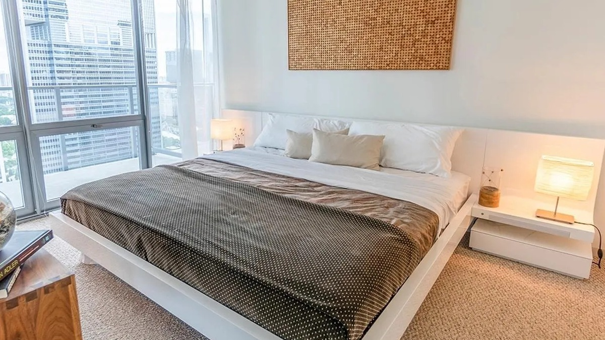 A cozy bedroom at Coast at Lakeshore East featuring a large bed, modern decor, and expansive city views