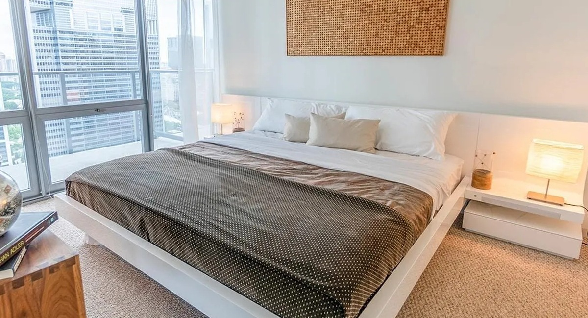 A cozy bedroom at Coast at Lakeshore East featuring a large bed, modern decor, and expansive city views