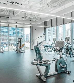 Modern fitness center with cardio equipment and city views at Coast at Lakeshore East apartments in Chicago