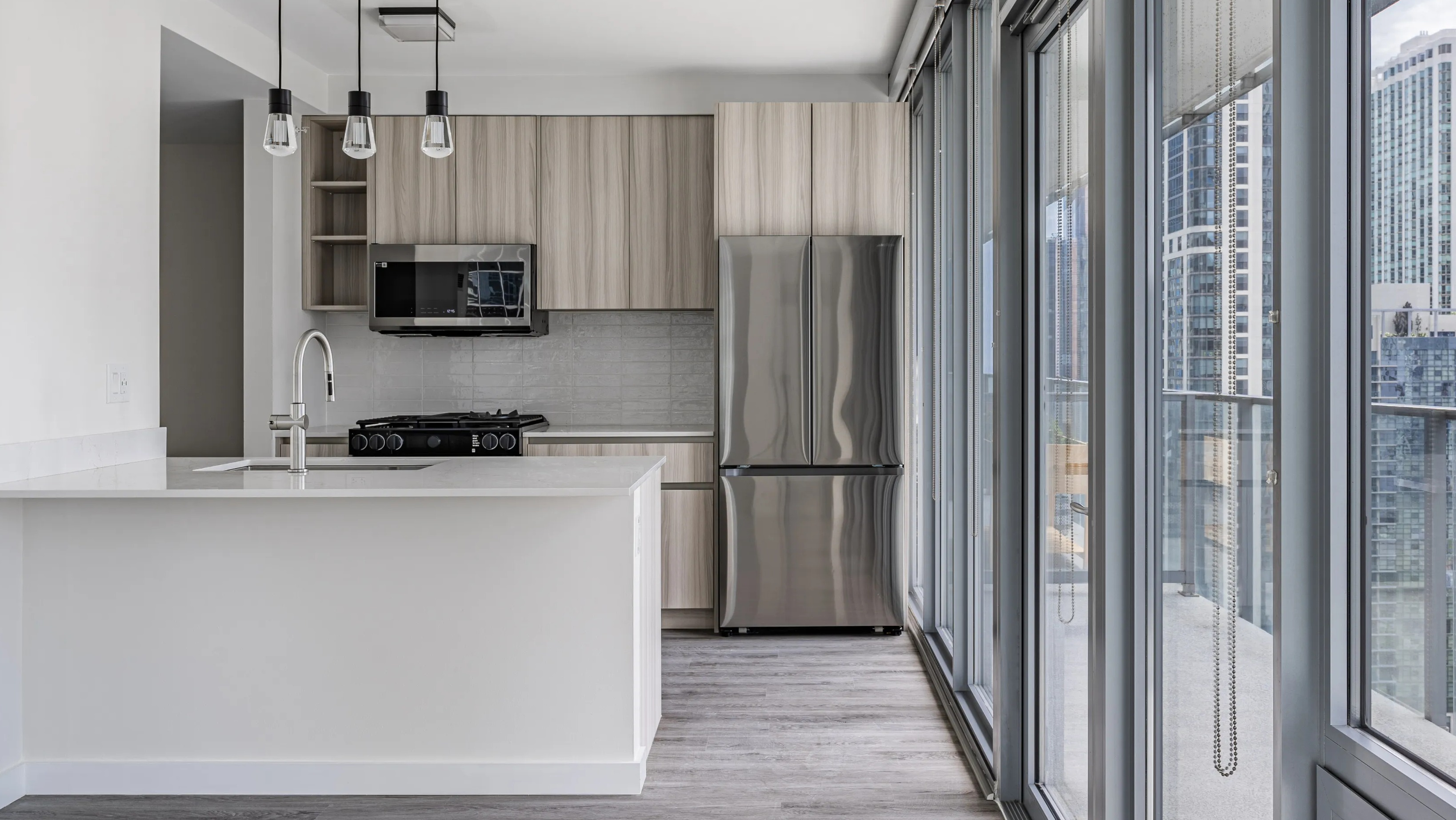 A bright modern kitchen in a Coast at Lakeshore East apartment, featuring stainless steel appliances and a city view