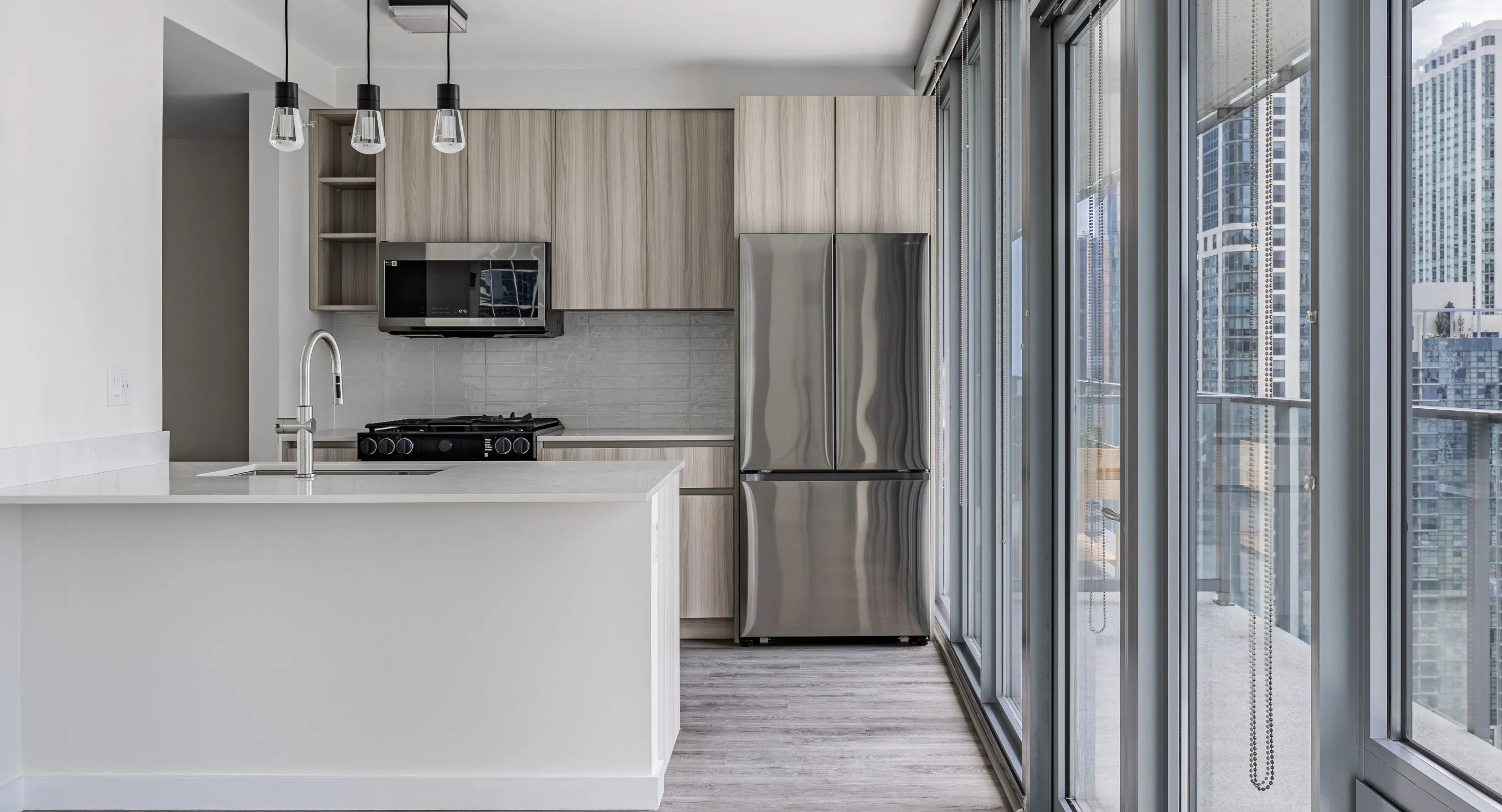 A bright modern kitchen in a Coast at Lakeshore East apartment, featuring stainless steel appliances and a city view