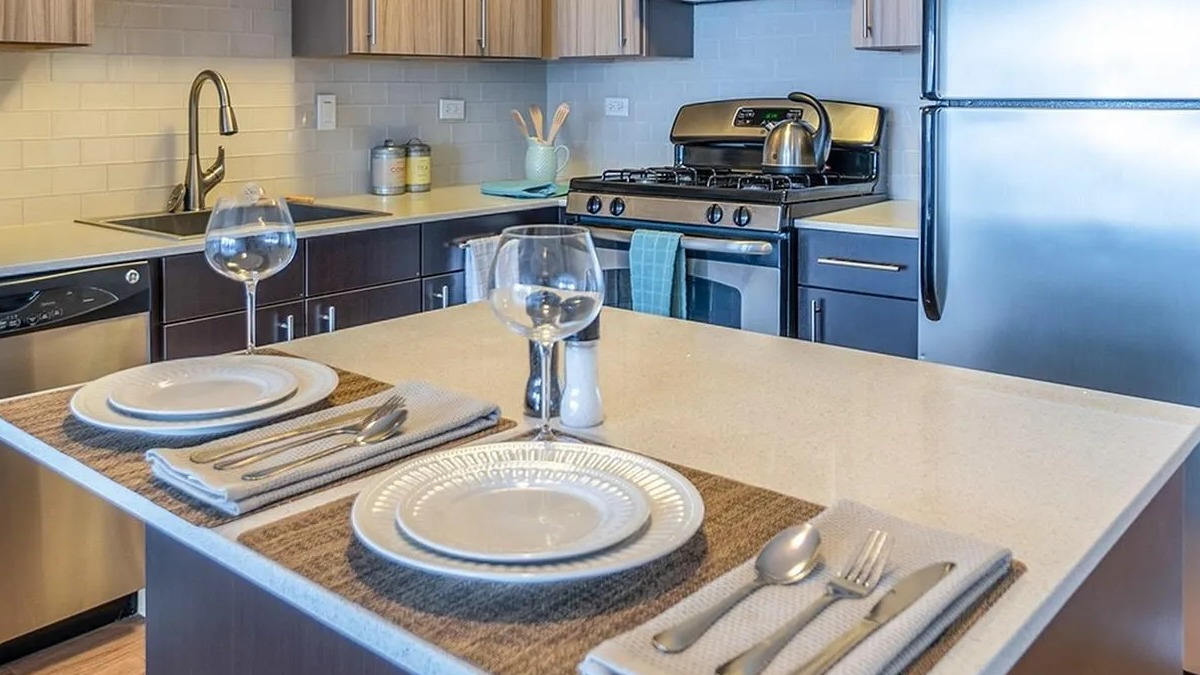 A contemporary kitchen at Coast at Lakeshore East, featuring stainless steel appliances and an island set for dining