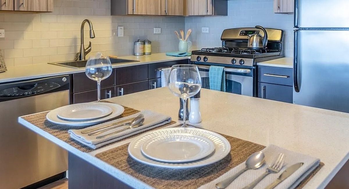 A contemporary kitchen at Coast at Lakeshore East, featuring stainless steel appliances and an island set for dining