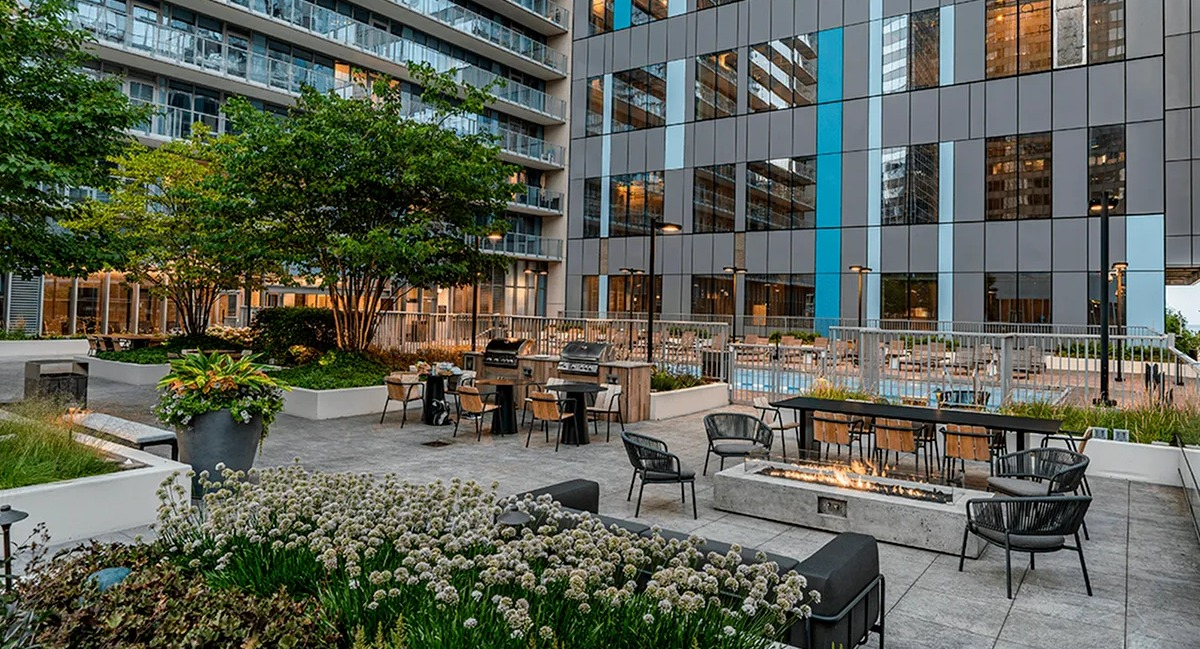 A beautifully landscaped courtyard at Coast at Lakeshore East with lush greenery, outdoor seating, and a pool in the background