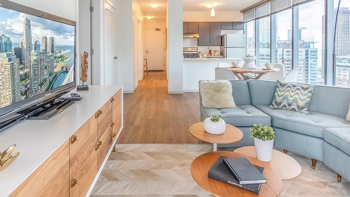 A spacious living room at Coast at Lakeshore East, showing an open flow into the modern kitchen area with city views
