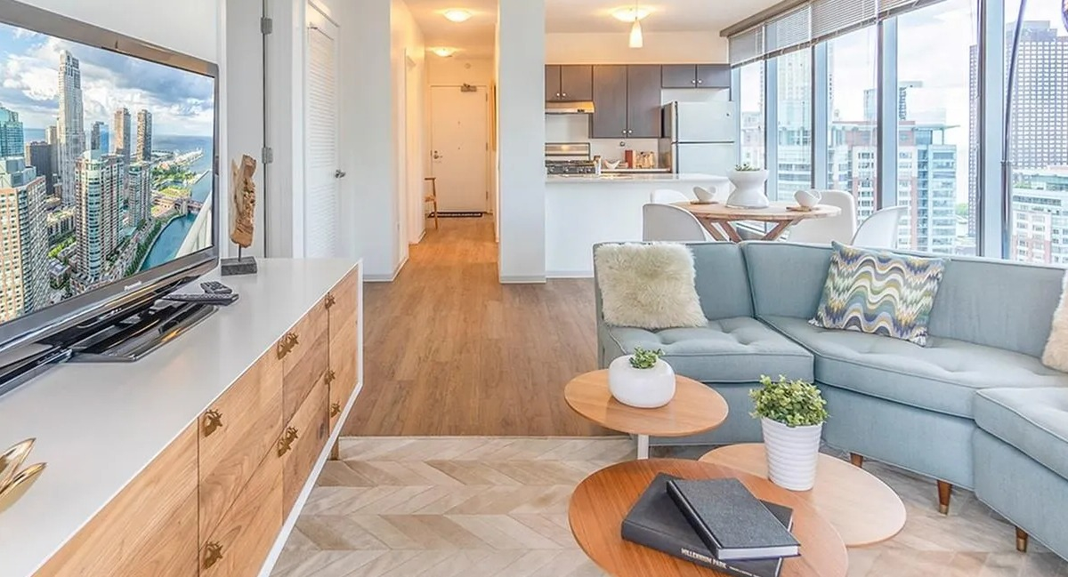 A spacious living room at Coast at Lakeshore East, showing an open flow into the modern kitchen area with city views