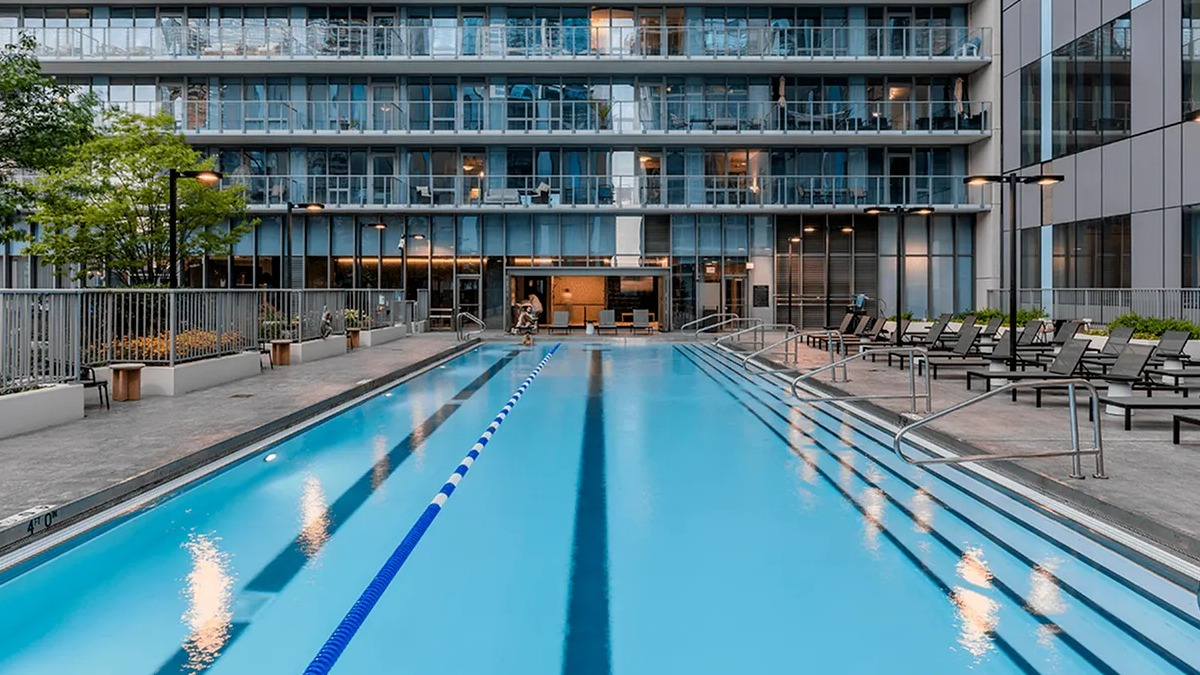 A pristine outdoor swimming pool at Coast at Lakeshore East during the day, with lounge chairs and building exteriors