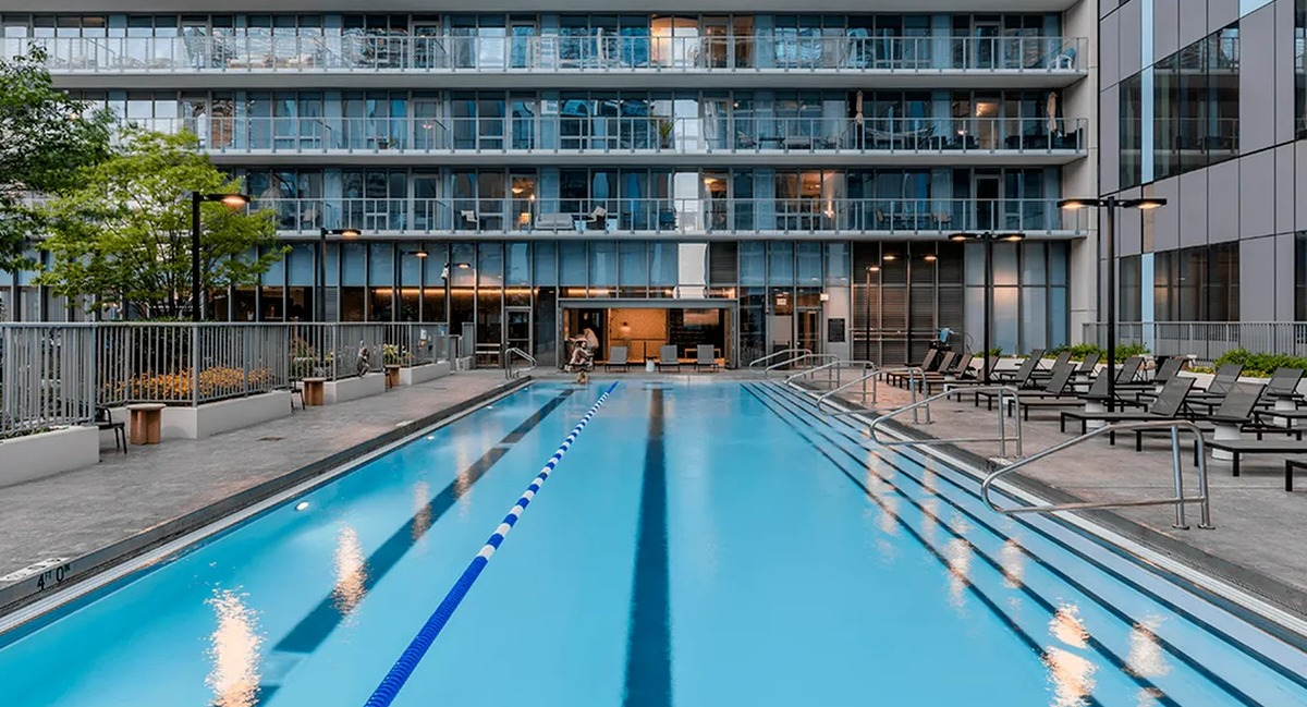 A pristine outdoor swimming pool at Coast at Lakeshore East during the day, with lounge chairs and building exteriors