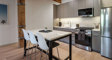 A chic kitchen with modern gray cabinetry, stainless steel appliances, and a dining island at Cobbler Square Lofts in Chicago