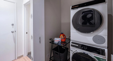 A dedicated laundry nook with stacked washer and dryer, providing ultimate convenience at Cobbler Square Lofts in Chicago