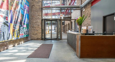 An inviting lobby with a reception desk, vibrant art, and large windows at the entrance of Cobbler Square Lofts in Chicago
