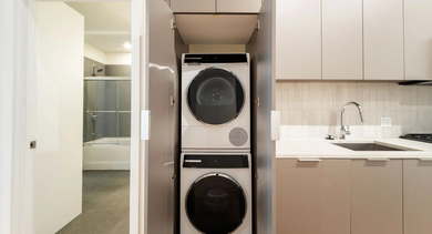 Modern kitchen with stacked in-unit washer and dryer, sleek cabinets, and stainless steel appliances at Cobbler Square Lofts in Chicago