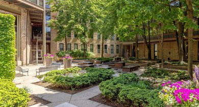Beautifully landscaped courtyard garden with lush greenery and vibrant flowers at Cobbler Square Lofts in Chicago